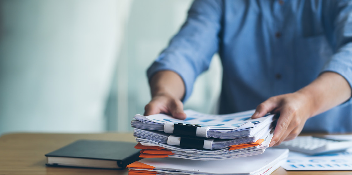 Personne empilant des documents sur un bureau