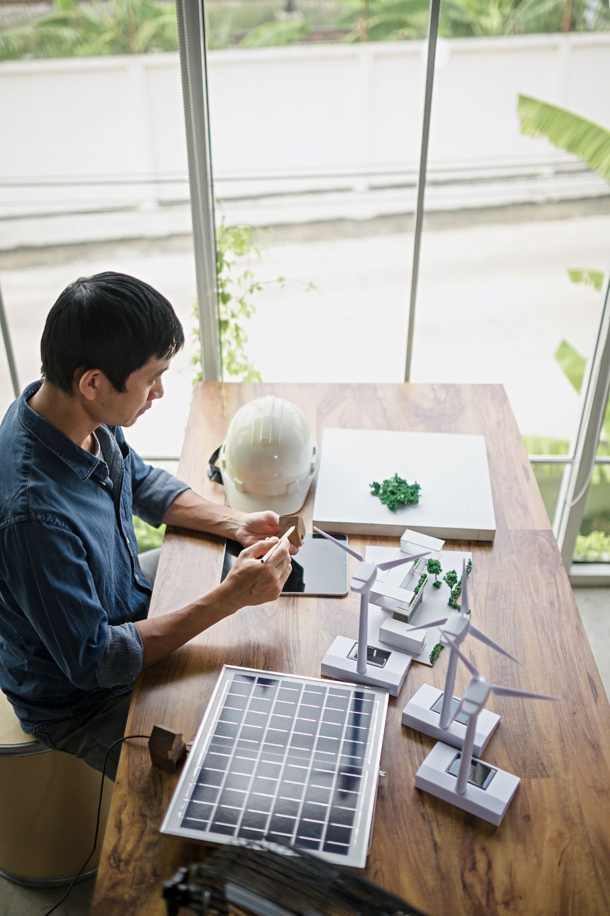Technicien travaillant avec des modèles de panneaux solaires et des éoliennes.
