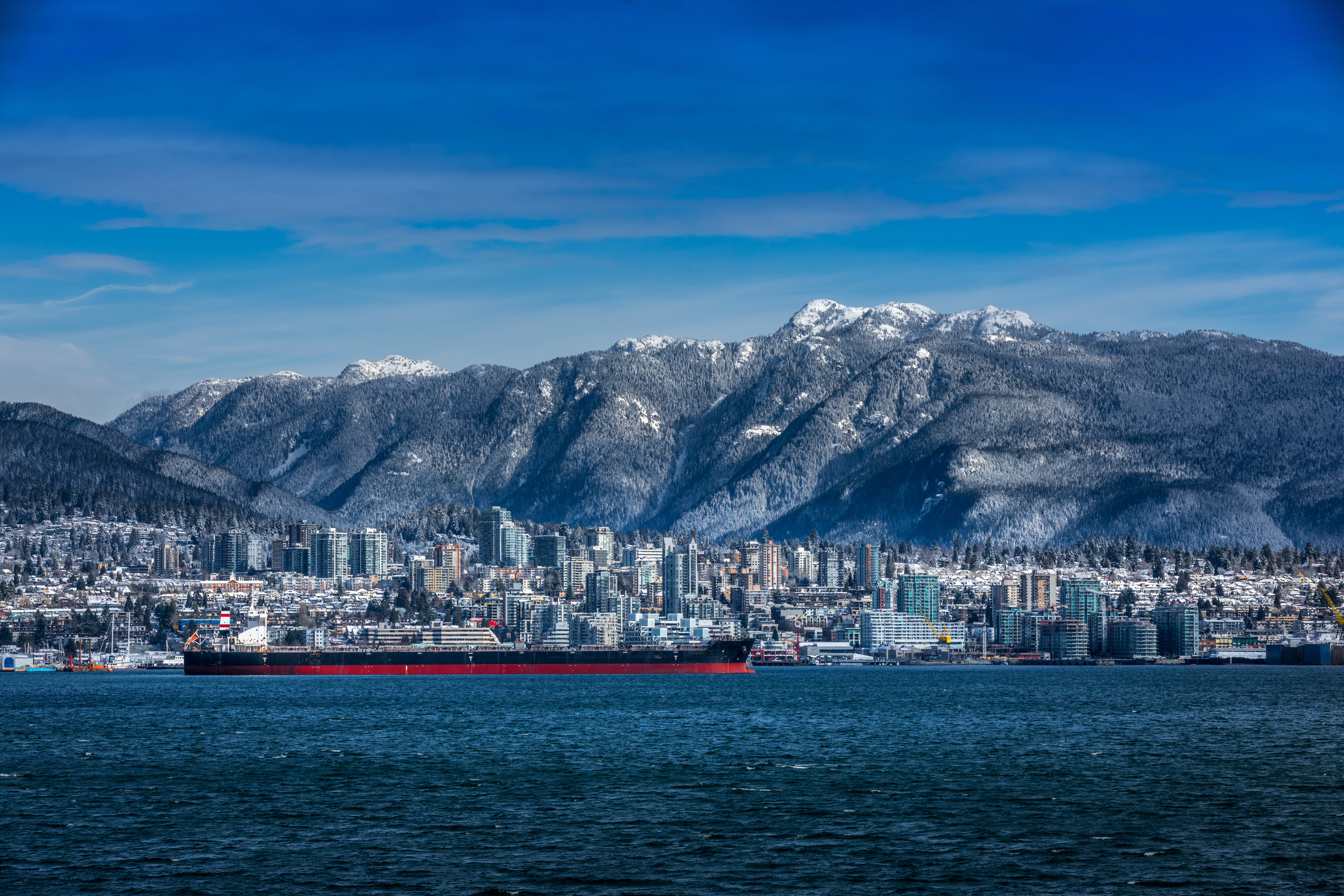 Un pétrolier sur l'eau, avec en arrière-plan la vue sur Vancouver-Nord et les Rocheuses recouvertes de neige.