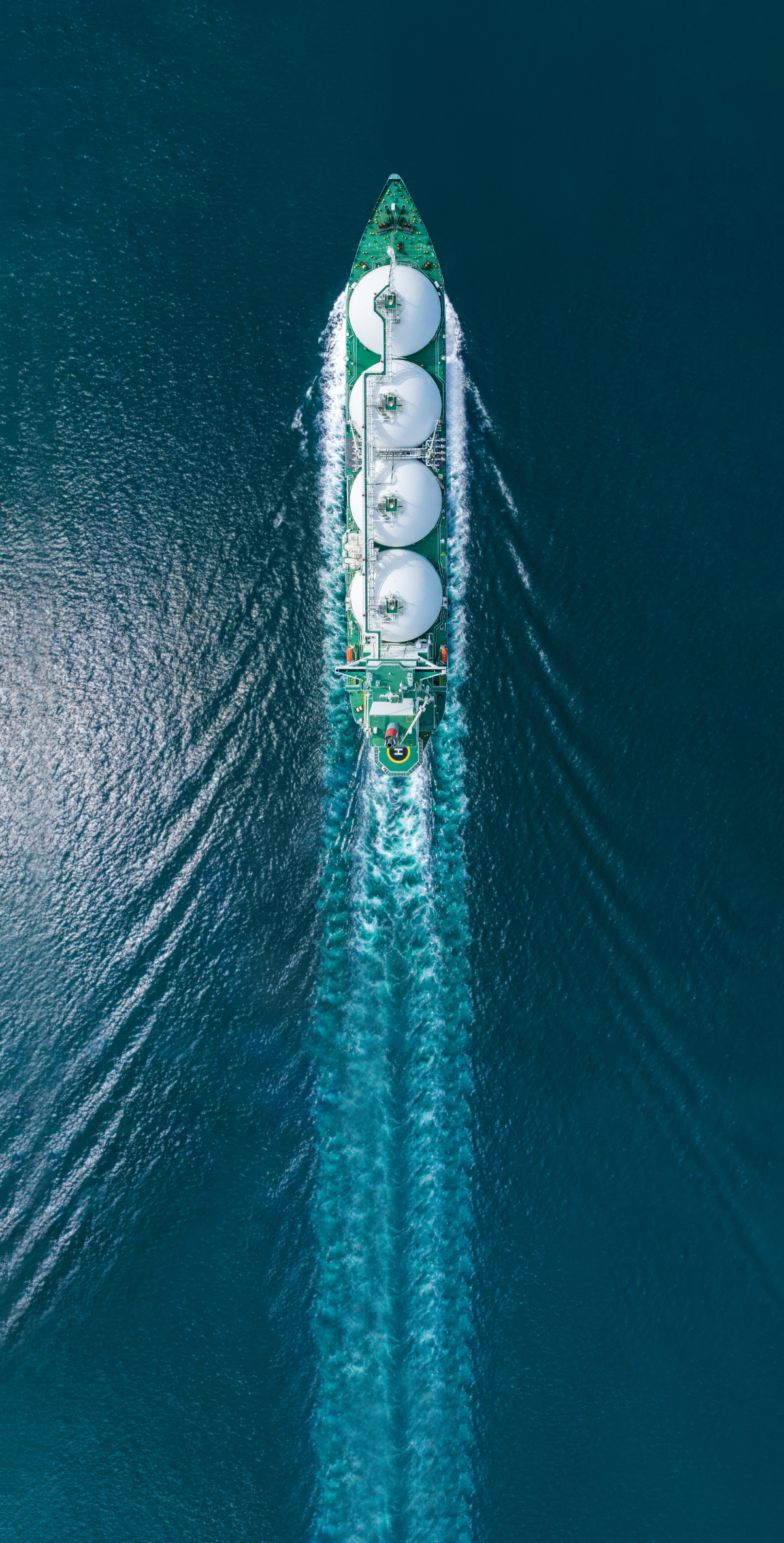 Vue aérienne d'un méthanier (navire transportant du gaz naturel liquéfié) avec son sillage dans l'océan.