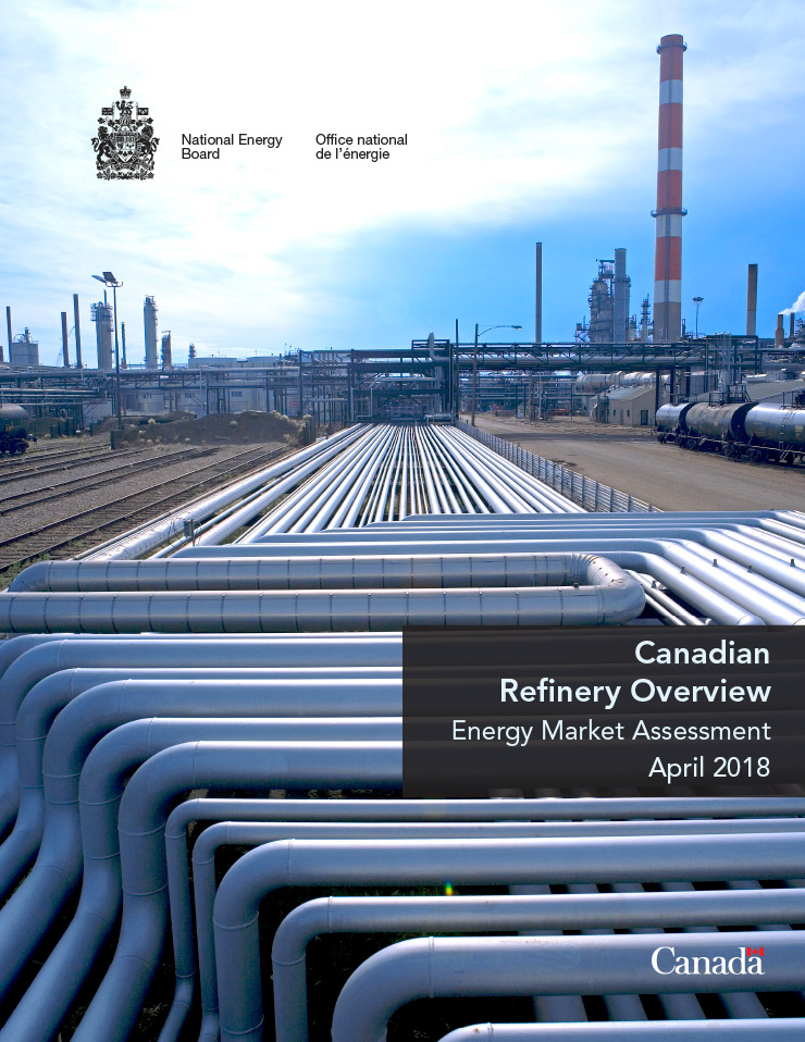 A close up view of pipes and stacks in the background of Canadian oil refinery on a partially cloudy day.