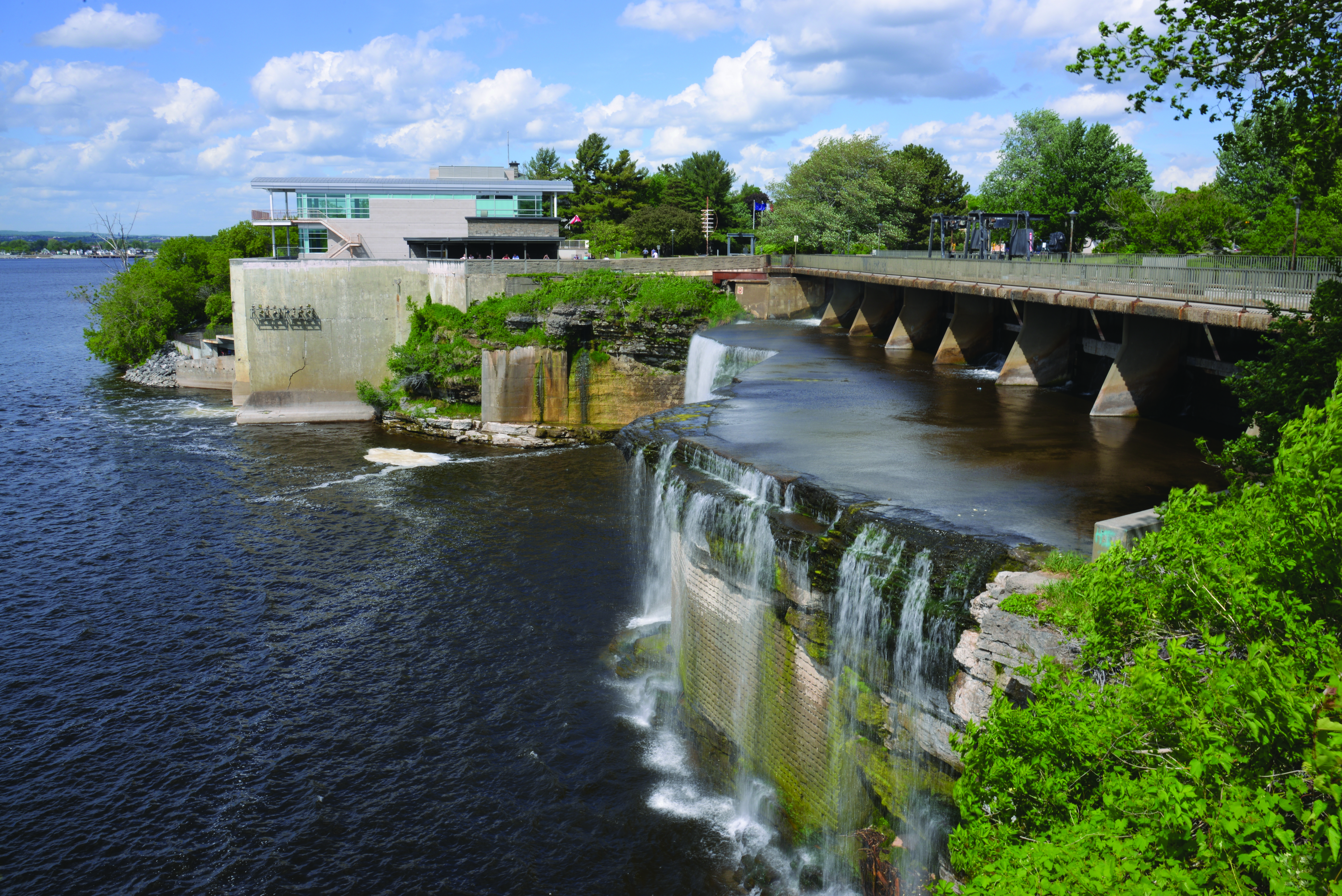 An image of Rideau falls and its hydroelectricity plant in Ottawa from an observation deck, on a cloudy summer day.