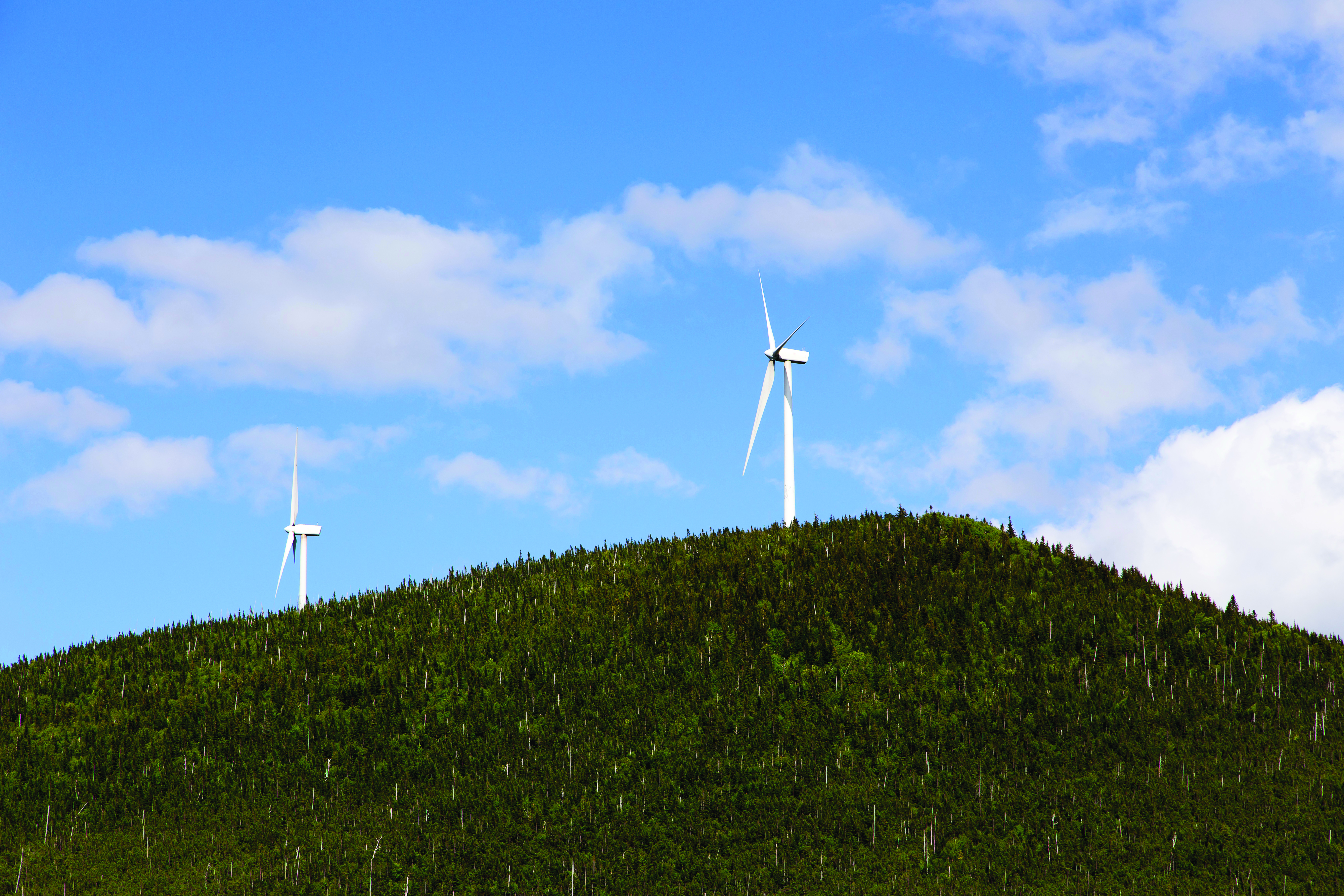 Two wind turbines on Mount Millar seen against blue sky during a sunny day in Murdochville, Quebec.