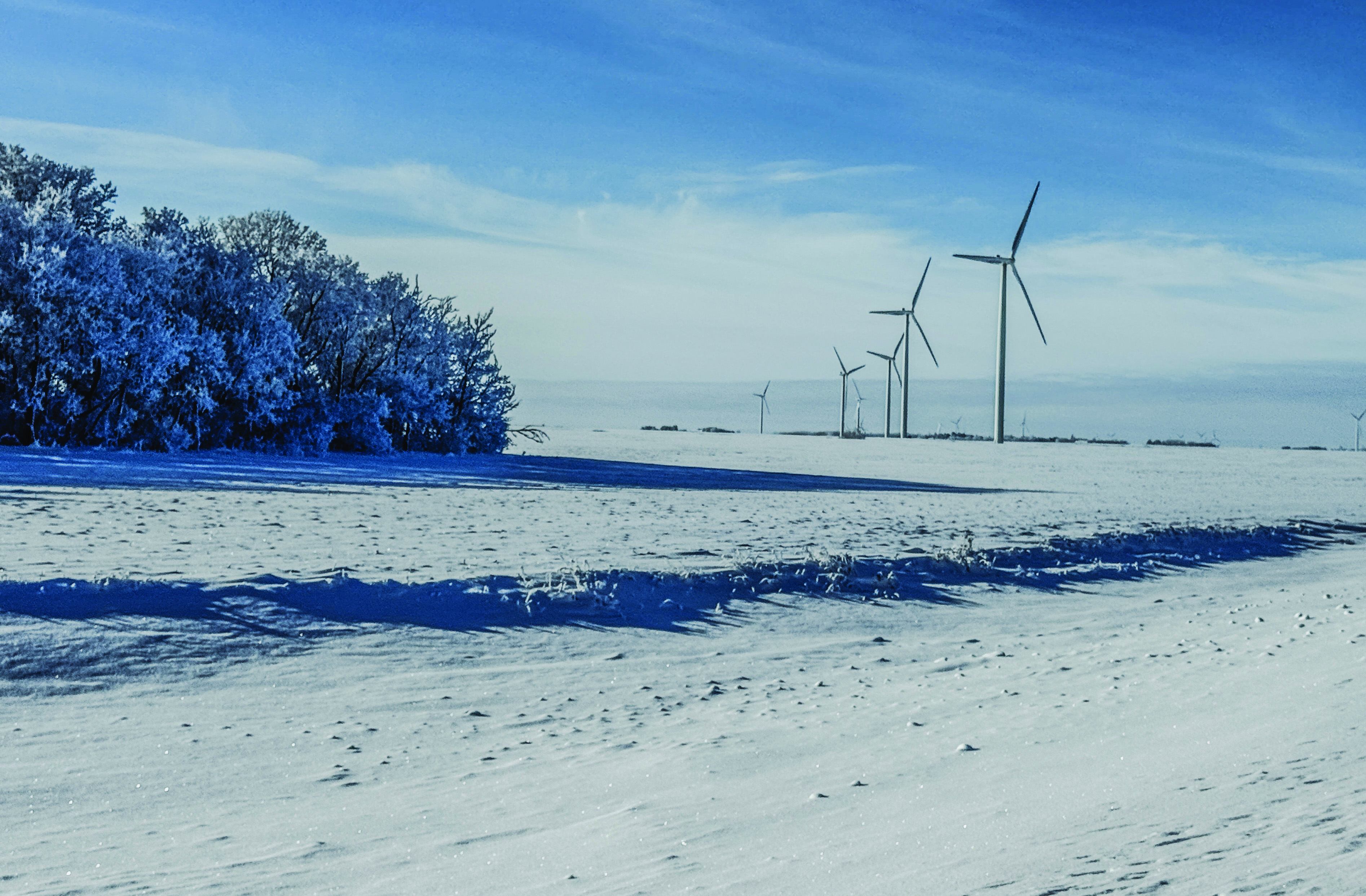 Wind turbines in snow covered fields in rural Manitoba on a cold winter day.